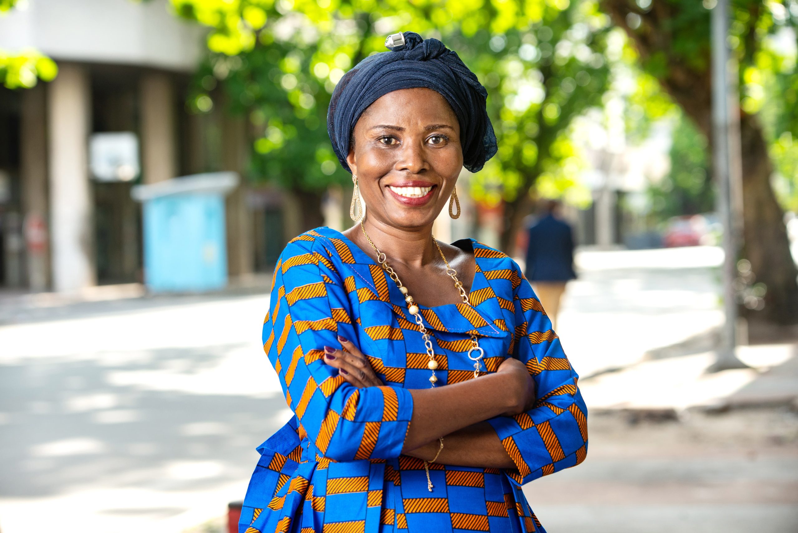 A woman standing with quiet confidence on a tree-lined street