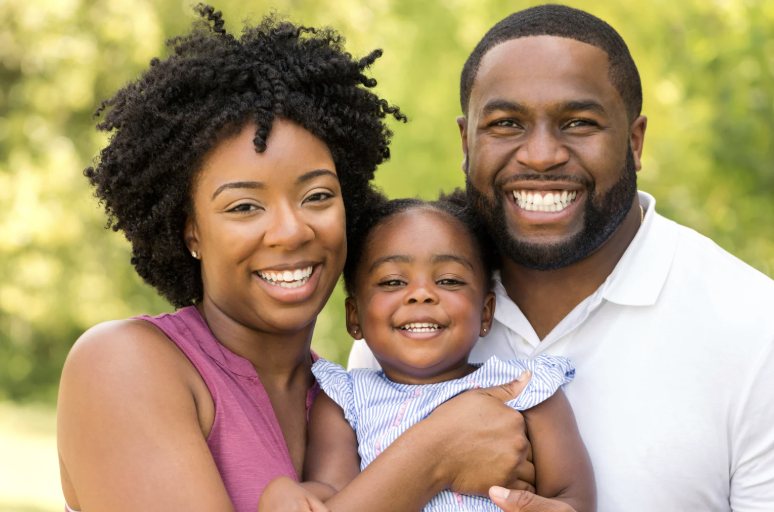 A mother, father, and their young daughter smiling together